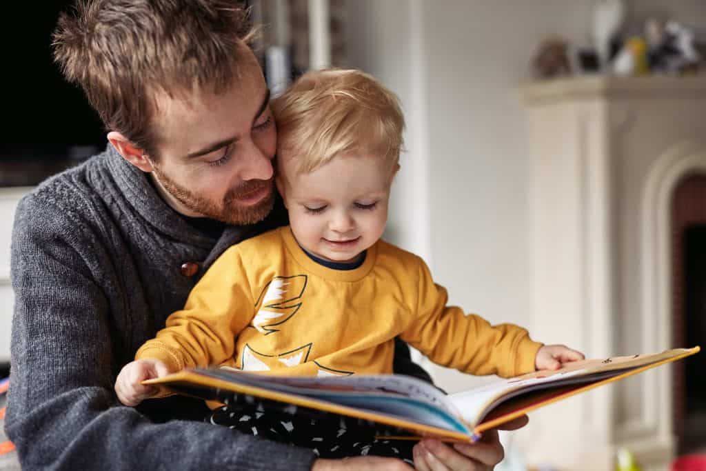 Dad and toddler son reading together
